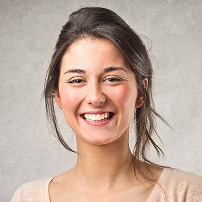 A woman smiling for the camera with her hair in a ponytail.