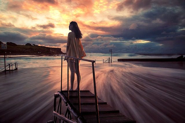 A woman standing on the steps to the beach.