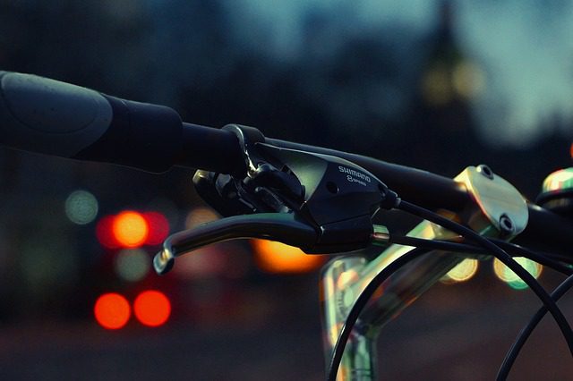 A bicycle handle bar with lights in the background.