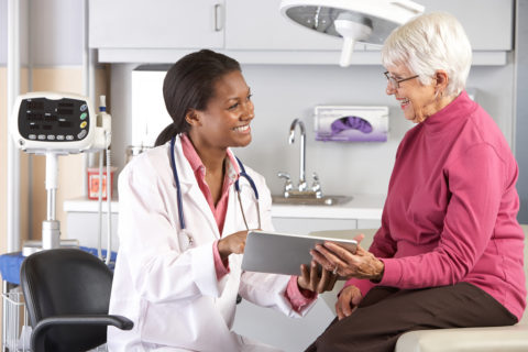 A doctor and patient in a room with a tablet.