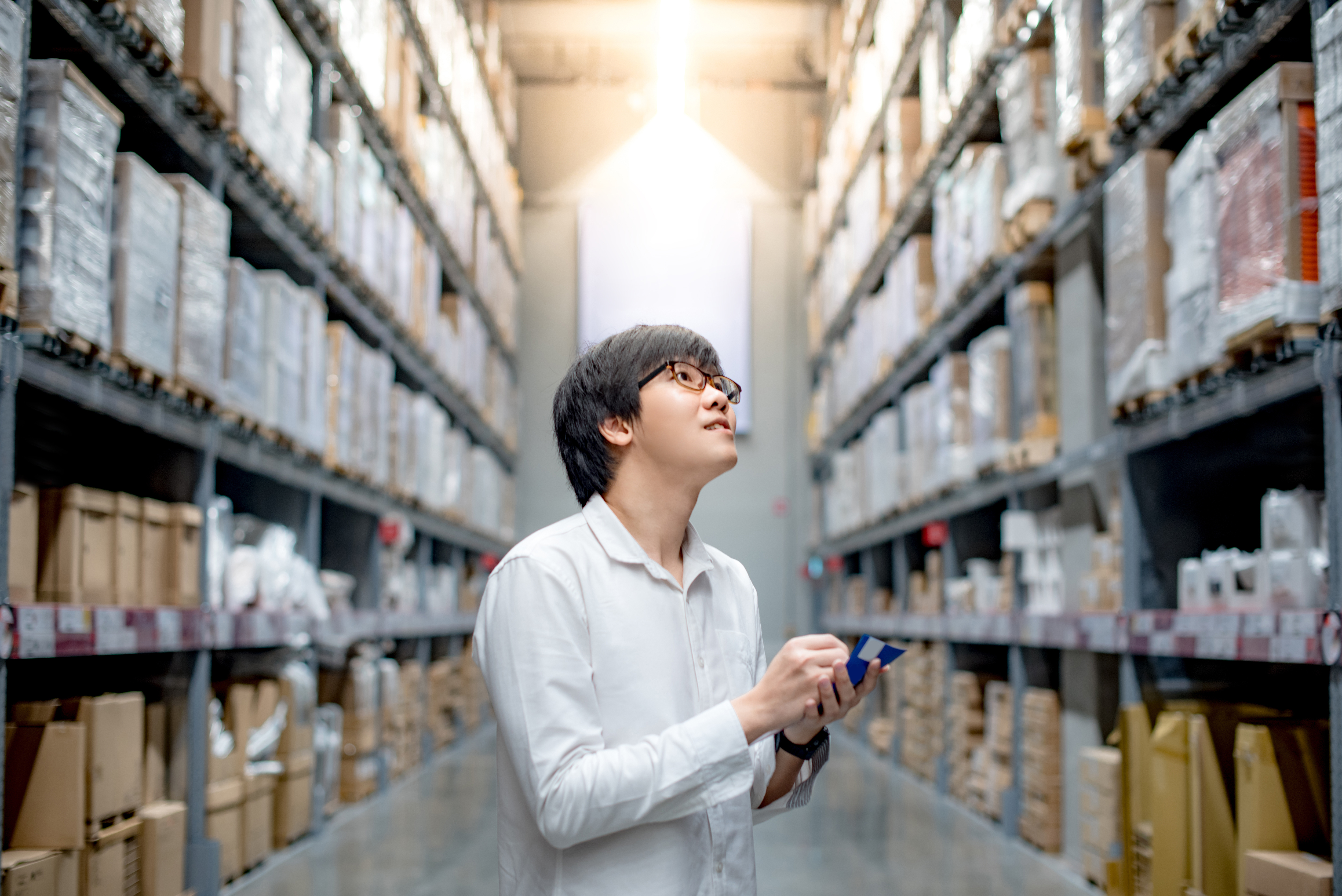 A man holding a pen in his hand while standing next to shelves.