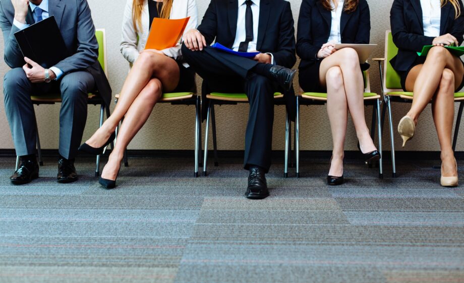 A group of people sitting in chairs with one person holding a folder.